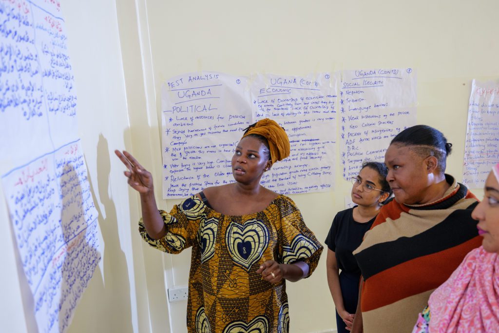 Ayak Chol Deng Alak, Inclusive Peace’s Peace Process Support Advisor, points at handwritten notes on the wall during a women’s coalition workshop on Ugandan political issues.